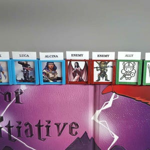 May include: A collection of miniature game pieces, each housed in a colored frame. The frames are blue, red, and green, with labels like "Tusk," "Luca," "Alcina," "Enemy," and "Ally." The game pieces feature various character illustrations.