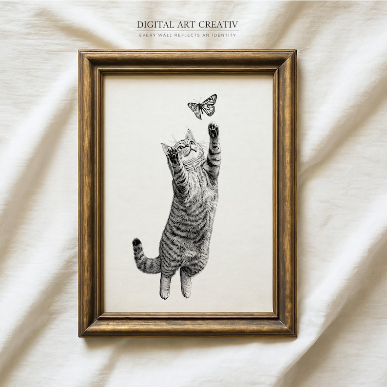 Pode incluir: Uma impress&atilde;o emoldurada em preto e branco com um gato brincalh&atilde;o alcan&ccedil;ando uma borboleta. O gato &eacute; retratado com listras detalhadas, em um fundo neutro. A moldura &eacute; marrom dourado quente. O texto na parte superior diz "DIGITAL ART CREATIV".