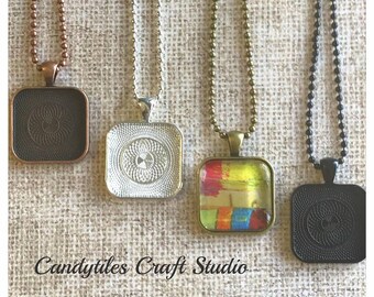 May include: Four square pendant trays with different chain styles. The trays are silver, bronze, black, and copper. The bronze tray has a colorful abstract design inside. The text "Candytiles Craft Studio" is at the bottom of the image.