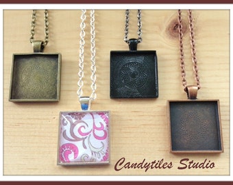 May include: Four square pendant trays with different colored metal frames and chains. The trays are empty except for one that has a pink and white patterned design inside.