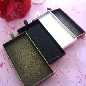 Puede incluir: Cuatro bandejas rectangulares de metal con una superficie texturizada. Las bandejas son de diferentes colores: dorado, negro, plateado y bronce. Las bandejas est&aacute;n apiladas, con la bandeja dorada en la parte inferior y la bandeja de bronce en la parte superior.