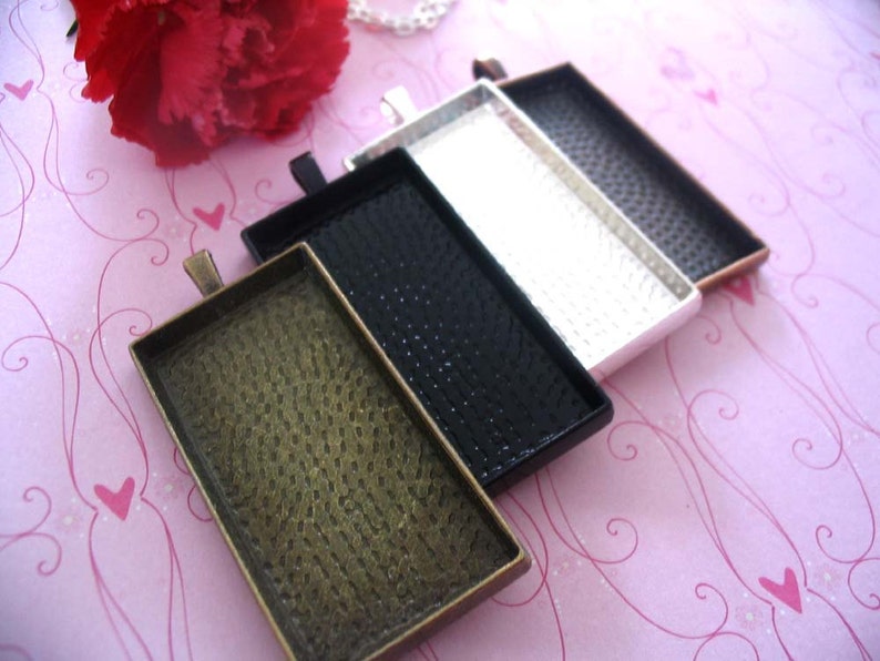 Puede incluir: Cuatro bandejas rectangulares de metal con una superficie texturizada. Las bandejas son de diferentes colores: dorado, negro, plateado y bronce. Las bandejas est&aacute;n apiladas, con la bandeja dorada en la parte inferior y la bandeja de bronce en la parte superior.