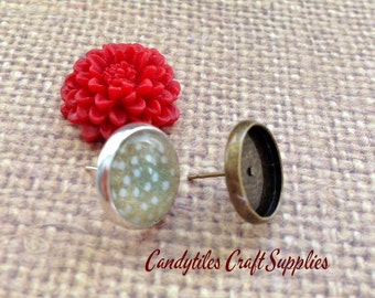 May include: Two silver earring settings with a white polka dot design on one setting and a blank setting on the other. The settings are on a brown burlap background.