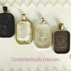 May include: Four different metal pendant trays with a decorative swirl pattern. The trays are rectangular and have a silver, black, gold, and bronze finish.