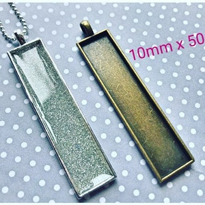 Peut inclure: Deux plateaux rectangulaires pour pendentifs en argent et bronze avec une finition scintillante. Les plateaux mesurent 10 mm x 50 mm.