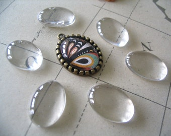 May include: Assortment of seven clear glass oval cabochons, perfect for jewelry making or crafting. The cabochons are various sizes and are displayed on a white surface with a black and white pattern.