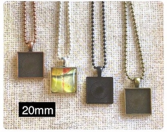 May include: Four silver pendant trays with chains, each measuring 20mm. The trays are square and have a black, silver, and clear glass finish.