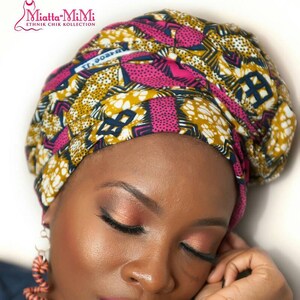 May include: A headwrap featuring a vibrant geometric pattern in shades of mustard yellow, magenta, and dark blue. The set includes matching fabric-covered bangles with the same colorful print and spiral-shaped dangling earrings.