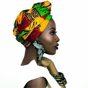 May include: A headwrap featuring a vibrant geometric pattern in shades of yellow, green, red, and black. The fabric is tied in a structured style. Large, textured, dark-toned statement earrings and a matching bracelet complement the headwrap.