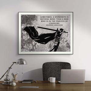 May include: A framed black and white art print with a silhouette of a figure holding a sword and cape. The print displays the quote "Sometimes, a hypocrite is nothing more than a man who is in the process of changing" by Brandon Sanderson.