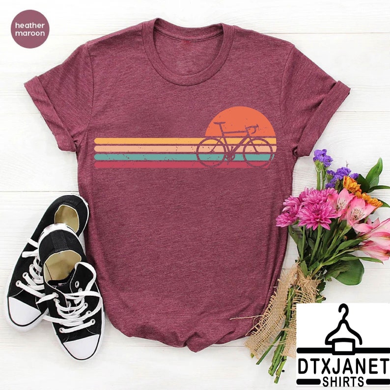 a t - shirt with a bicycle on it next to a bouquet of flowers