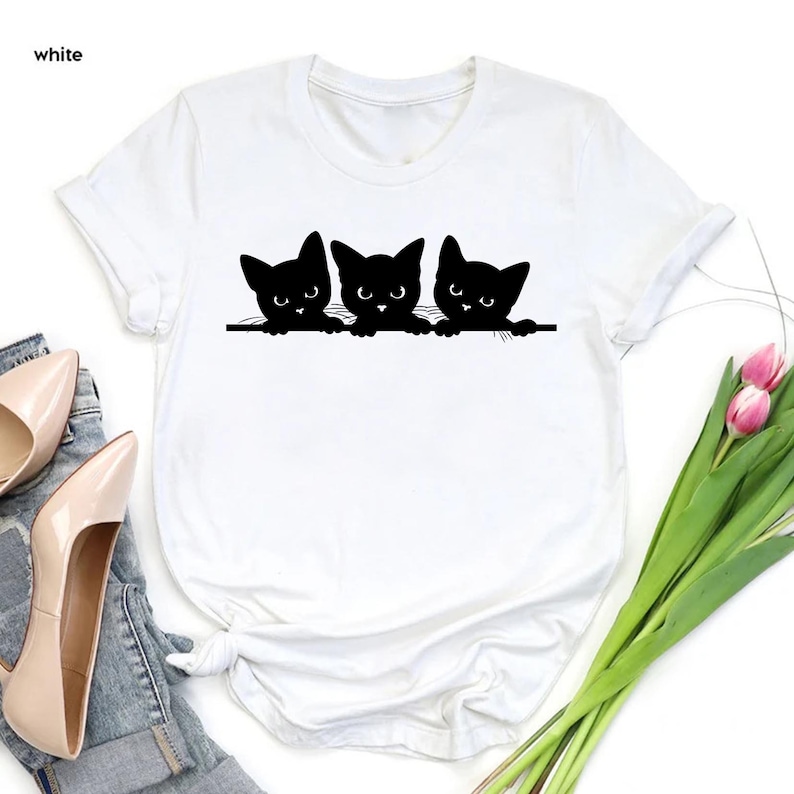 a white shirt with three black cats on it