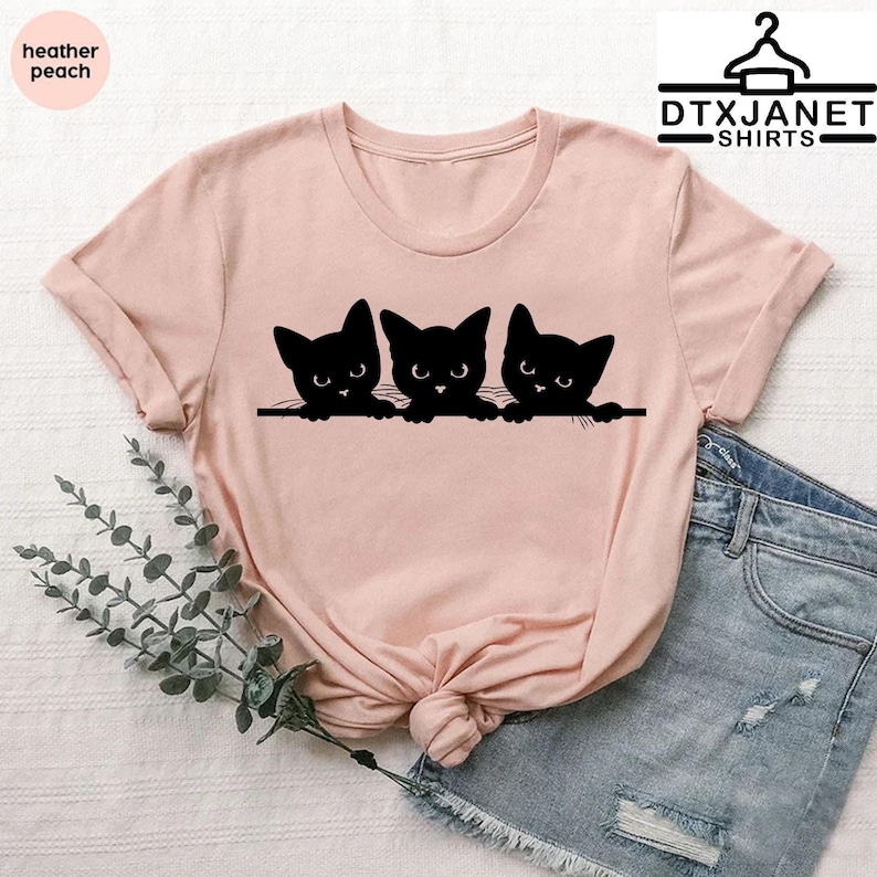 a pink shirt with three black cats on it