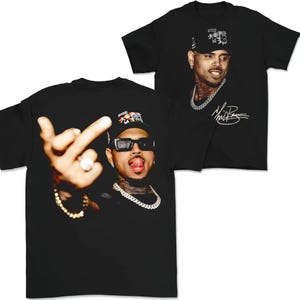 May include: Black t-shirts featuring a portrait of a man wearing a baseball cap, sunglasses, and a chain necklace. One shirt shows the man giving the middle finger. The other shirt shows the man with a signature.