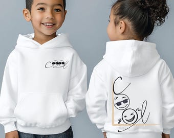 May include: Two children wearing white hoodies with the word "cool" and a smiling face graphic. The hoodie on the left has the word "cool" with a smiling face graphic on the front. The hoodie on the right has the word "cool" with a smiling face graphic on the back.