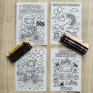 May include: Four white coloring pages with birthday-themed illustrations and crayons. The pages feature motorcycles, helmets, balloons, and the phrases "Vroom Birthday," "Ethan is Turning," and "Happy Birthday." Crayons are packaged in clear plastic.