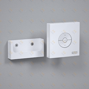 Puede incluir: Un panel de control blanco montado en la pared y un soporte a juego. El panel de control tiene un botón circular con flechas direccionales y la marca "VELUX". El soporte tiene dos tornillos.