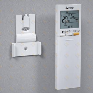 Puede incluir: Mando a distancia blanco Mitsubishi Electric para aire acondicionado, con pantalla digital que muestra 20°C y las 10:15. Está junto a un soporte de pared blanco. El mando tiene botones de temperatura y encendido/apagado.