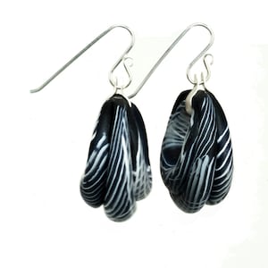 May include: A pair of black and white striped dangle earrings with silver hooks.