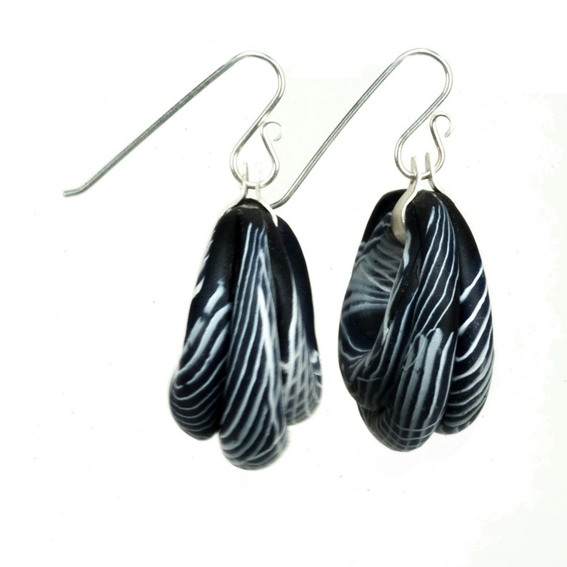 May include: A pair of black and white striped dangle earrings with silver hooks.