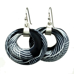 May include: A pair of black and white patterned hoop earrings with silver hooks.
