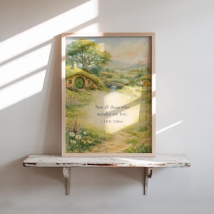 May include: Framed watercolor print featuring a serene landscape with hobbit-hole homes, a bridge, and a winding path. The print includes the quote "Not all those who wander are lost" by J.R.R. Tolkien.