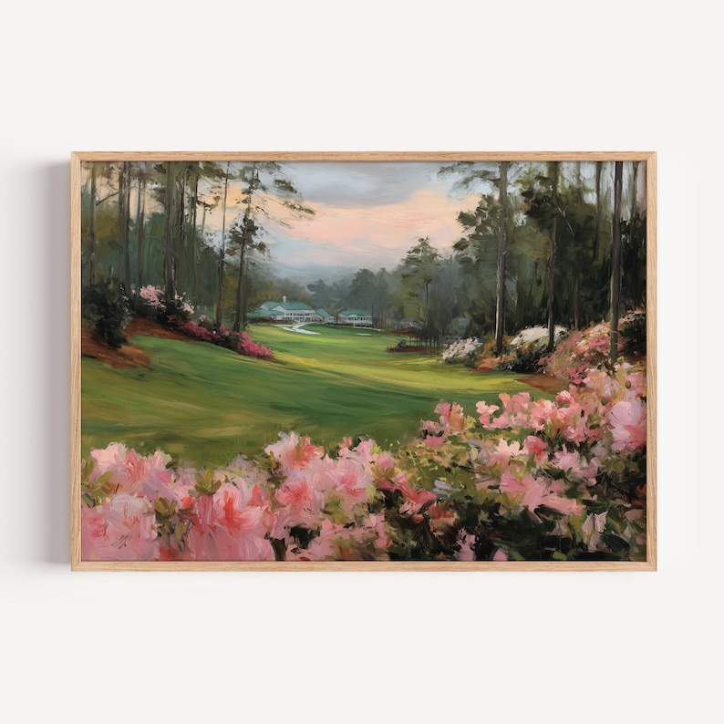 Puede incluir: Pintura de paisaje enmarcada de un campo de golf con una calle verde, &aacute;rboles y un edificio al fondo. Flores rosas y blancas en primer plano. La obra de arte est&aacute; en un marco de madera.