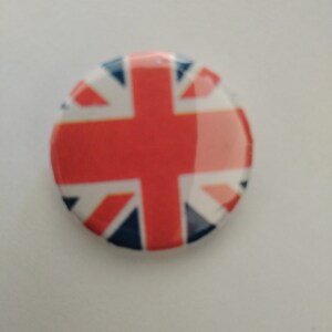 Op de afbeelding: Een ronde knoop met een ontwerp van een Union Jack-vlag in rood, wit en blauw.