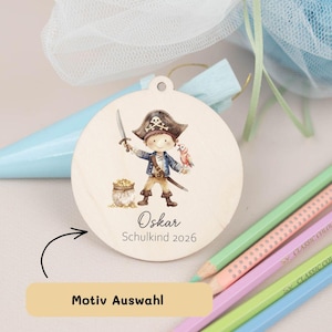 Könnte beinhalten: Runder Holzschmuck mit einer Illustration eines Piraten mit Schwert, Papagei und Schatz. Mit Loch zum Aufhängen und dem Namen "Oskar" sowie dem Text "Schulkind 2026".