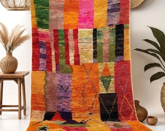 May include: A colorful Moroccan rug with a geometric pattern in shades of red, orange, yellow, green, pink, and purple. The rug has a fringe border and is made of wool.