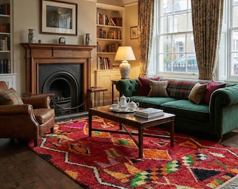 May include: A cozy living room with a red patterned rug, a green velvet sofa, and a wooden coffee table. The room features a fireplace, bookshelves, and a leather armchair. The curtains and pillows have a plaid pattern.