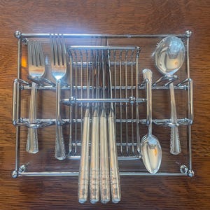 May include: A rectangular chrome-plated wire caddy holding a set of silver-toned flatware. The organizer features dedicated slots for two forks on the left, a central section for four knives, and two spoons on the right, all arranged in a grid.