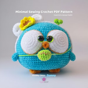 Peut inclure: Un poussin bleu crocheté avec des yeux blancs et une feuille verte dans son bec. Le poussin porte un chapeau crocheté blanc avec une fleur jaune sur le dessus. Le poussin est assis sur un fond blanc. Le texte "Chubby Chick - Sunny" est sous le poussin.