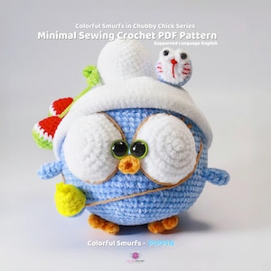 May include: A blue crocheted amigurumi toy in the shape of a chick wearing a white crocheted hat with a red and green crocheted flower on the side. The chick has large white eyes with green pupils and a small orange beak. The chick is holding a yellow crocheted object in its right hand.