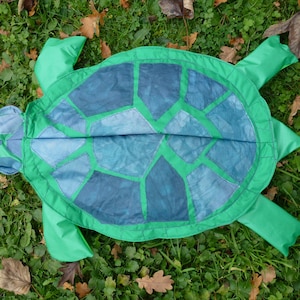 May include: A green turtle costume with a blue and green shell. The shell is made of fabric and has a patchwork design.