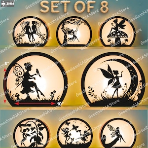 Op de afbeelding: Set van 8 decoratieve lampen met feeënthema. Elke lamp heeft een zwart silhouetontwerp in een cirkelvormig frame, met verschillende feeënscènes. De lampen zijn ongeveer 25 cm breed en 20 cm hoog, met een warme, gloeiende binnenkant.
