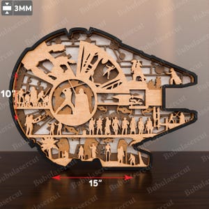 May include: A multi-layered wooden wall art piece shaped like a spaceship, featuring intricate laser-cut silhouettes of characters and scenes. It measures 10 inches in height, 15 inches in width, and is 3mm thick, with the text STAR WARS visible.