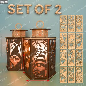 May include: Set of 2 wooden lanterns with gnome and sunflower cutouts. Each lantern is approximately 7 inches wide, 11 inches tall. Includes additional decorative panels with gnome designs. The text "SET OF 2" is displayed at the top.