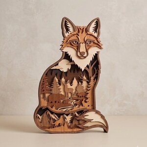 May include: A multi-layered wooden wall art piece shaped like a fox. The interior cutout features a detailed forest scene with a deer, a bear, a smaller fox, and a wolf silhouette against a moonlit background, rendered in various shades of brown.