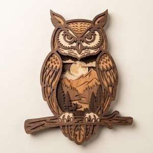 May include: A multi-layered wooden wall art piece shaped like an owl perched on a branch. The design features a dark brown owl silhouette with intricate cutouts revealing a light tan landscape of mountains, a full moon, pine trees, and a deer.