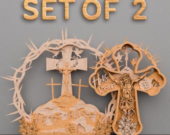 Puede incluir: Conjunto de dos decoraciones de cruz de Pascua de madera cortadas con láser. Una cruz presenta una corona de espinas y las palabras "Ha resucitado". La otra cruz presenta una figura de Jesús en la cruz con las palabras "No está aquí, ¡Ha resucitado!" y "Yo soy la resurrección y la vida".