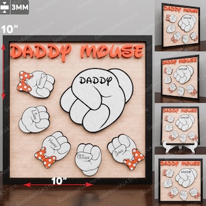 May include: A framed wooden sign that reads "DADDY MOUSE" in orange letters. The sign features a large white cartoon hand with the word "DADDY" and smaller hands with names and red bow ties. The sign is 10 inches wide and 10 inches tall.