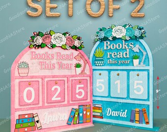 May include: Set of two wooden book trackers, one pink and one blue, each with a floral top. The pink tracker reads "Books Read This Year" and shows "025" with "Laura" below. The blue tracker reads "Books read this year" and shows "515" with "David" below. Each is 7 inches wide and 9 inches tall.