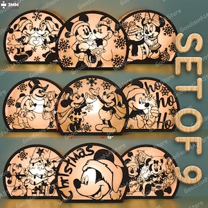 Op de afbeelding: Een set van negen kerst-thema Mickey Mouse en vrienden silhouetlampen. Elke lamp heeft een uniek ontwerp, waaronder Mickey en Minnie Mouse, sneeuwmannen en vakantiegroeten. De lampen zijn ongeveer 25 cm breed.