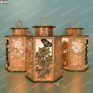 May include: Three wooden lanterns with laser-cut floral and butterfly designs. Each lantern is approximately 11 inches tall and 7 inches wide. The lanterns have a warm, inviting glow, perfect for home decor.