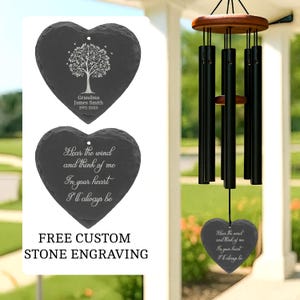 May include: Heart-shaped memorial stone with a tree engraving and the text "Grandma James Smith 1971-2025". Another heart-shaped stone has the text "Hear the wind and think of me. In your heart I'll always be". A wind chime hangs nearby.