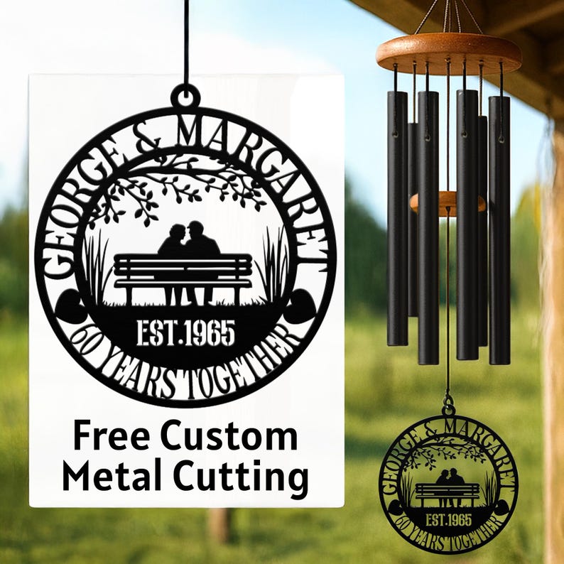 Op de afbeelding: Een zwart metalen windgong met een cirkelvormig uitgesneden ontwerp van twee mensen op een bankje onder een boom, met de tekst George & Margaret, Est. 1965 en 60 Years Together. De windgong heeft een houten bovenkant en vijf zwarte metalen buizen.