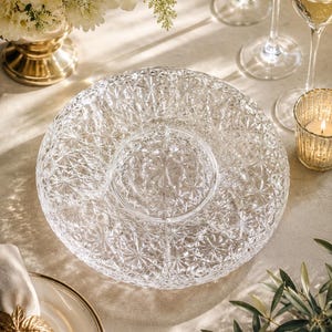 Peut inclure: Un plat de service en verre transparent présentant un motif géométrique et en étoile pressé sur toute sa surface. Ce plat circulaire possède une section centrale lisse et surélevée ainsi qu'un bord texturé pour présenter des aliments.