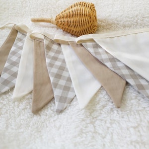 Può includere: Un'insegna di bandierine in tessuto gingham beige e bianco. L'insegna è realizzata in morbido tessuto di cotone e ha uno stile rustico e da fattoria.