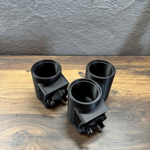以下が含まれることがあります： 3Dプリントされた黒いプラスチック製のカップホルダー3個